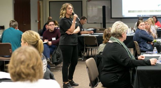 woman speaking to seated group with microphone