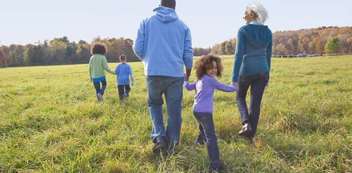 family walking and holding hands in a field